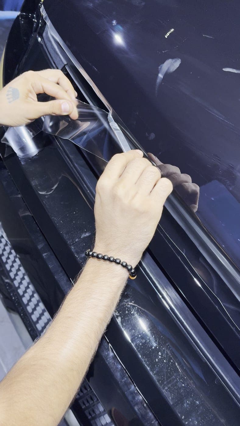 Film liner peeled back along a hood edge