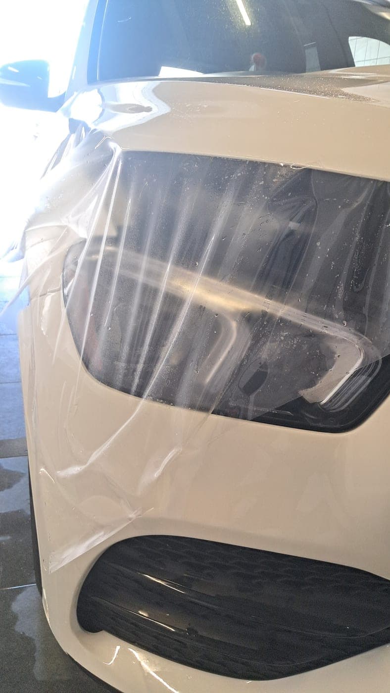 Clear film laid over a white Mercedes headlight and bumper